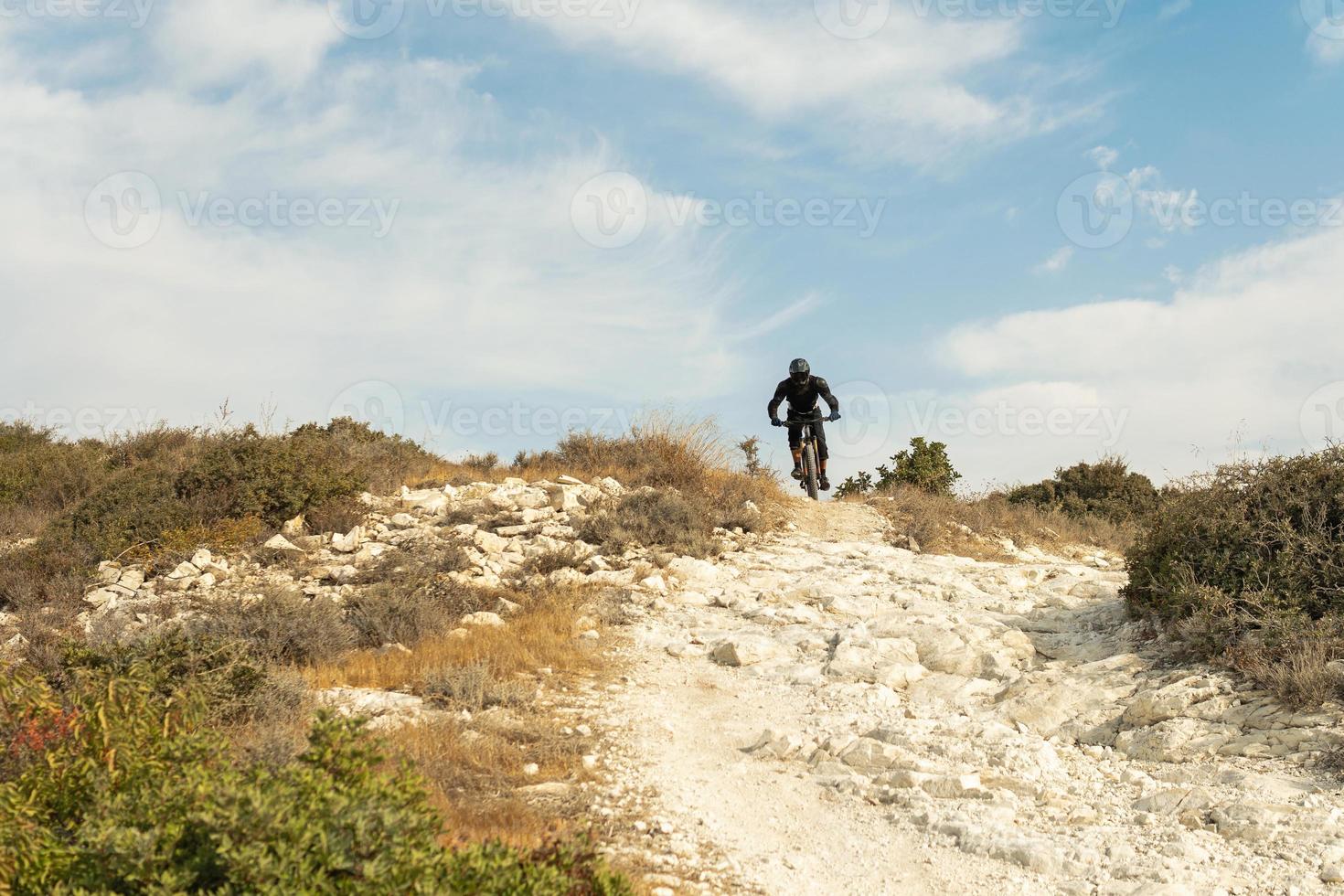 Rider fully equipped with protective gear during downhill ride on his bicycle photo