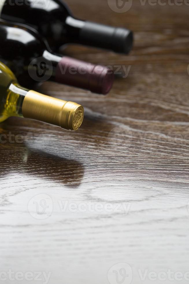 Various Wine Bottles on Reflective Wood Surface Abstract photo