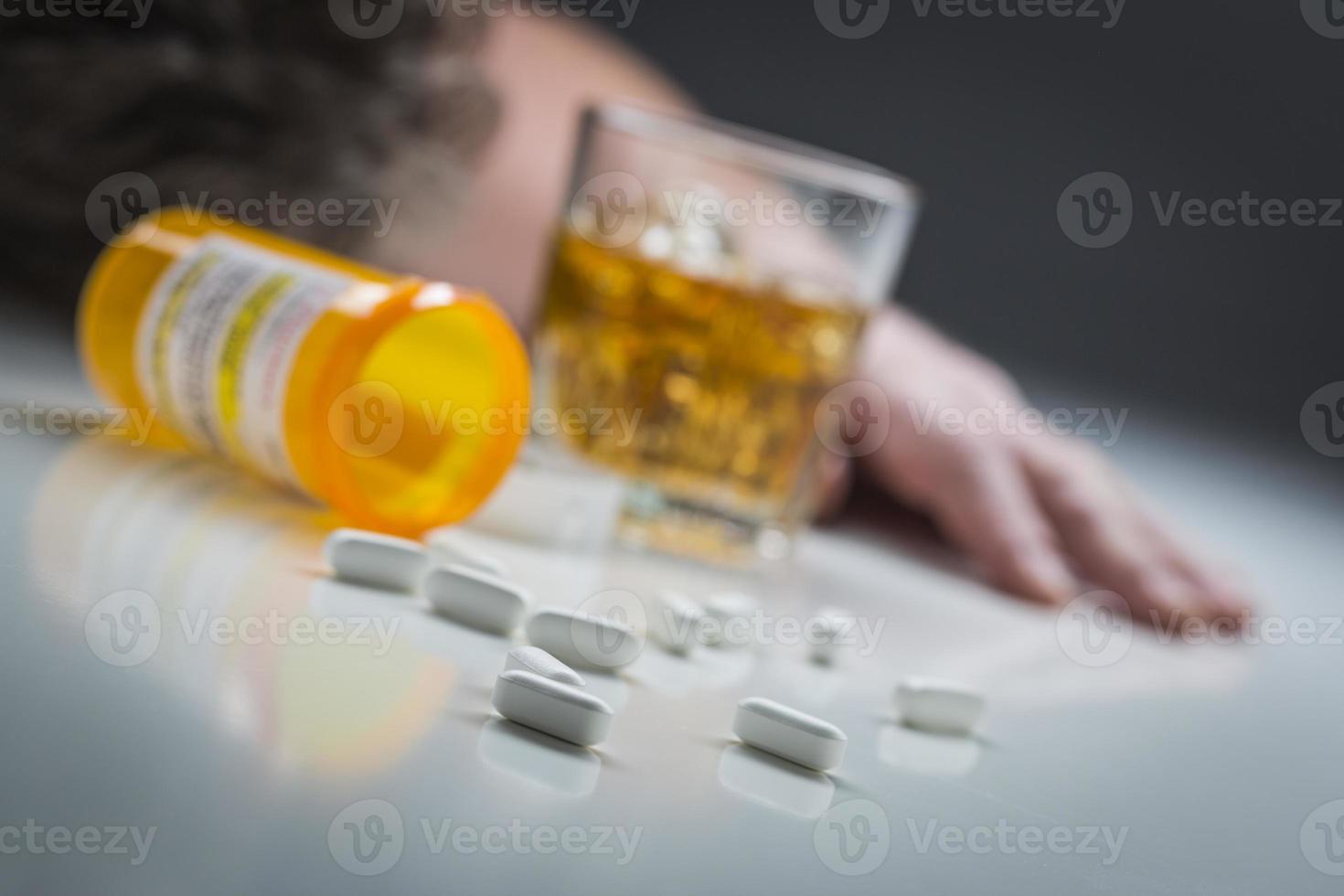 hombre desmayado detrás de drogas dispersas y un vaso de alcohol foto