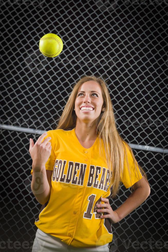 retrato de jugador de softbol femenino con pelota en el aire. foto