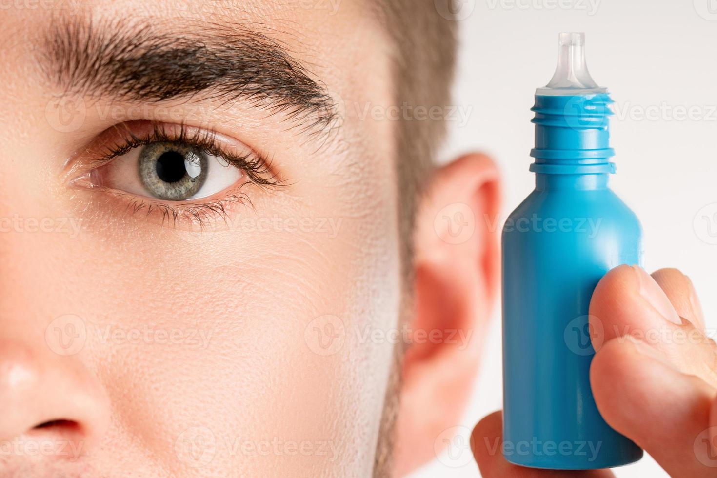 Male eye and small bottle of eyedrops photo