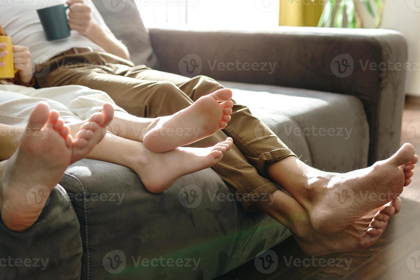Barefoot family sitting on sofa in the living room photo