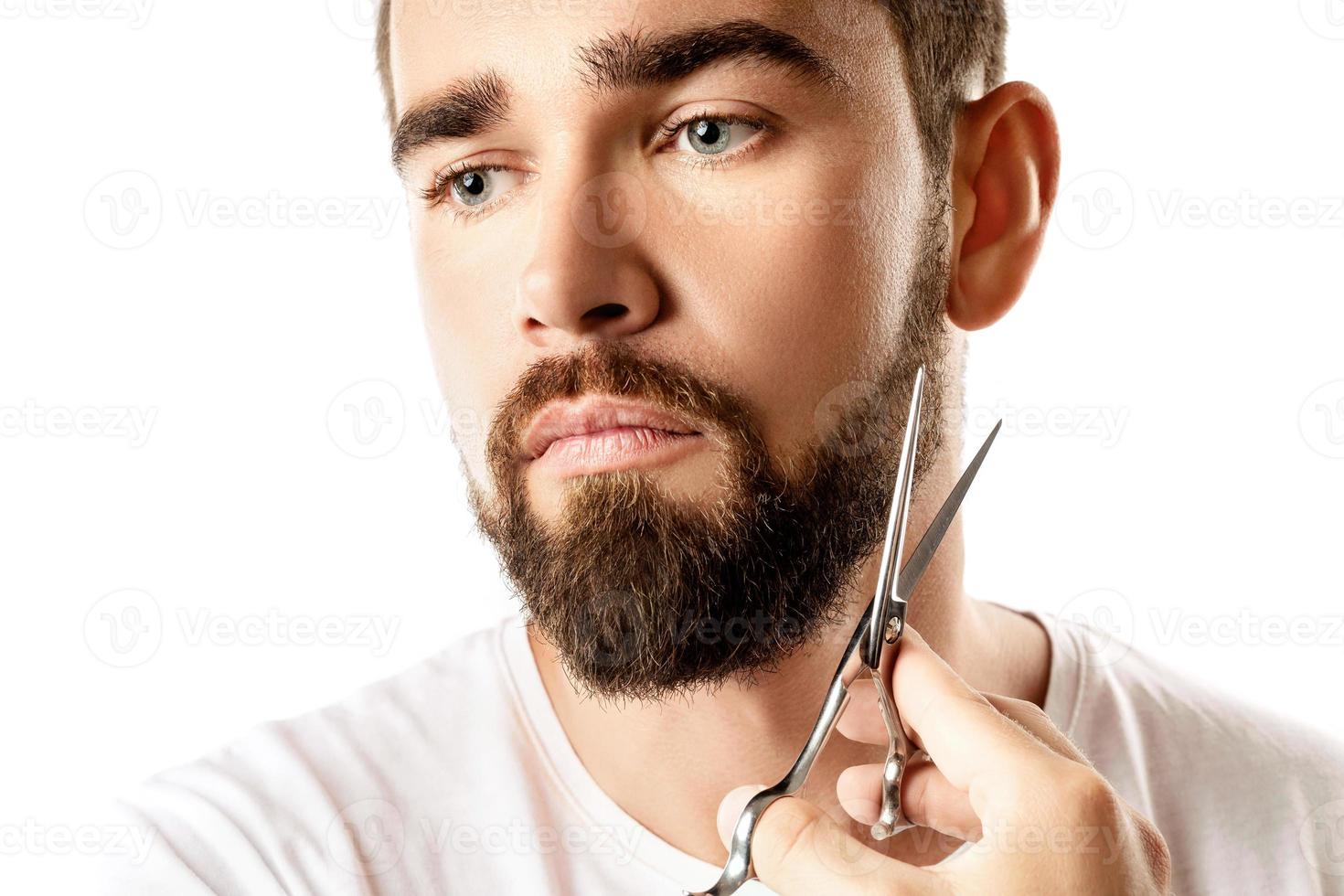 hombre guapo recortando su barba con unas tijeras foto