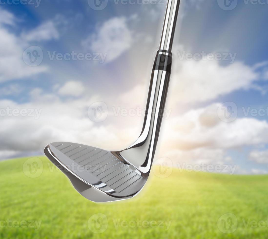 Chrome Golf Club Wedge Iron Against Grass and Blue Sky Background photo