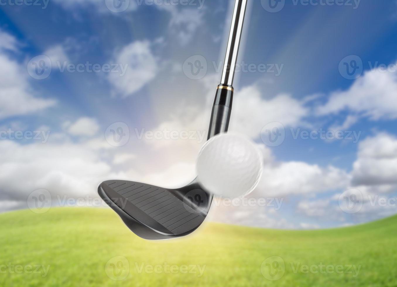 Black Golf Club Wedge Iron Hitting Golf Ball Against Grass and Blue Sky Background photo