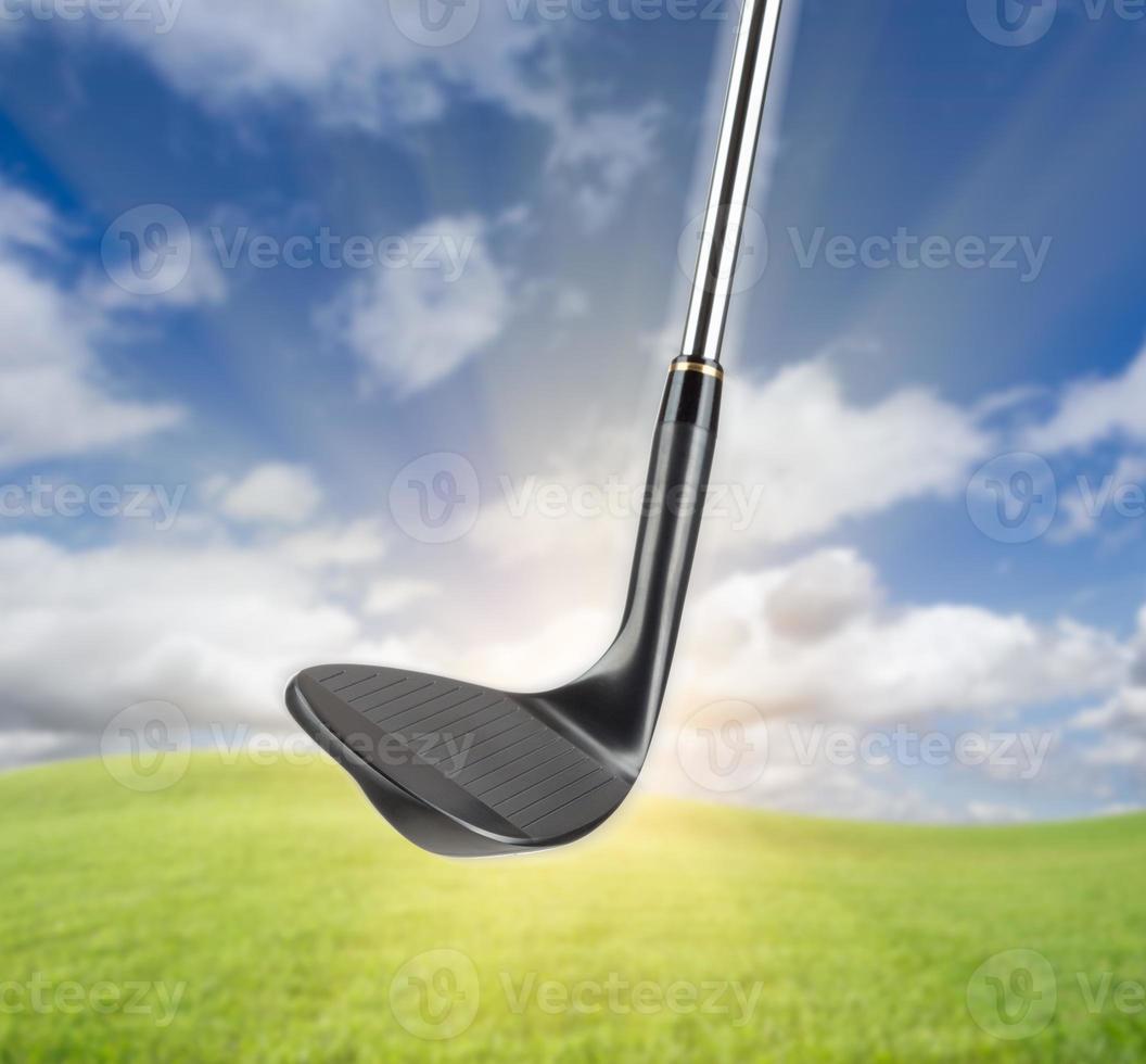 Black Golf Club Wedge Iron Against Grass and Blue Sky Background photo