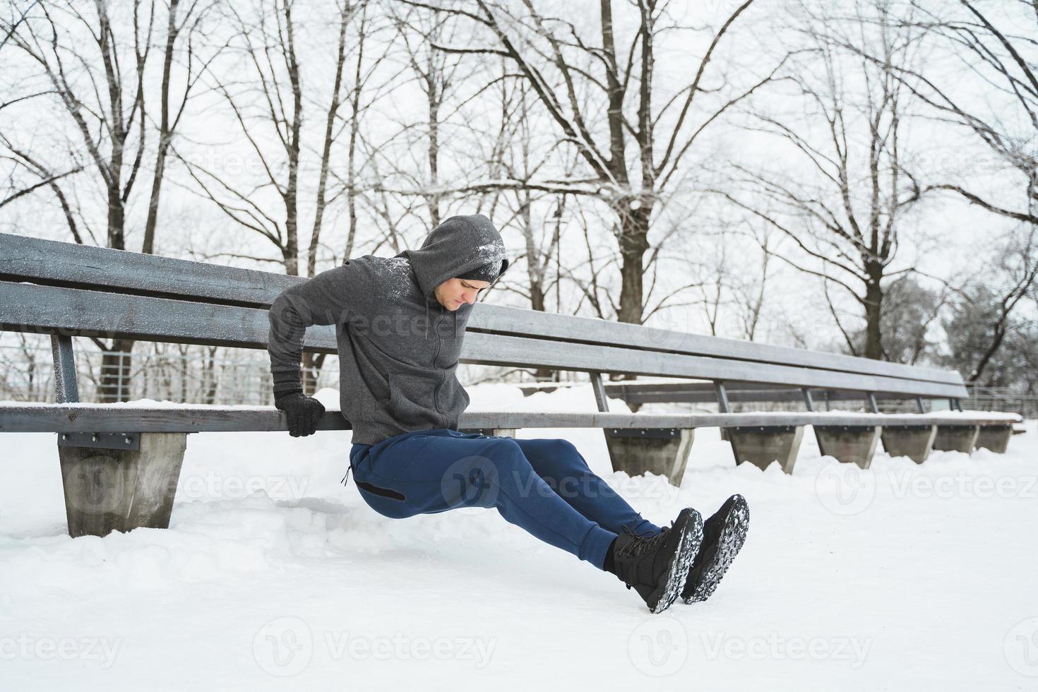 Athletic man doing push ups during his calisthenics winter workout photo