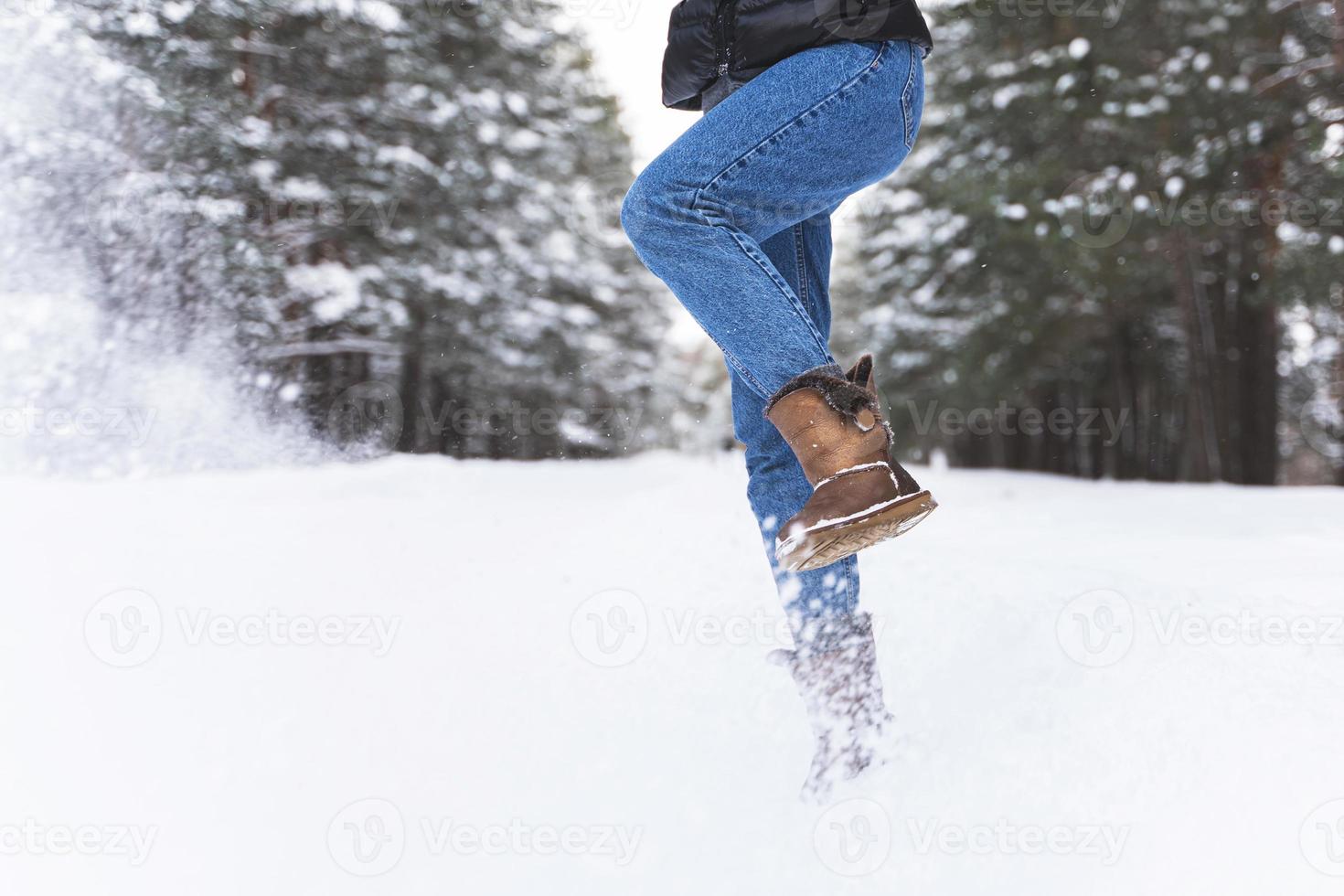 Woman wearing sheepskin boots is kicking snow photo