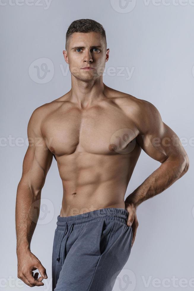 culturista mostrando su cuerpo musculoso contra el fondo gris foto