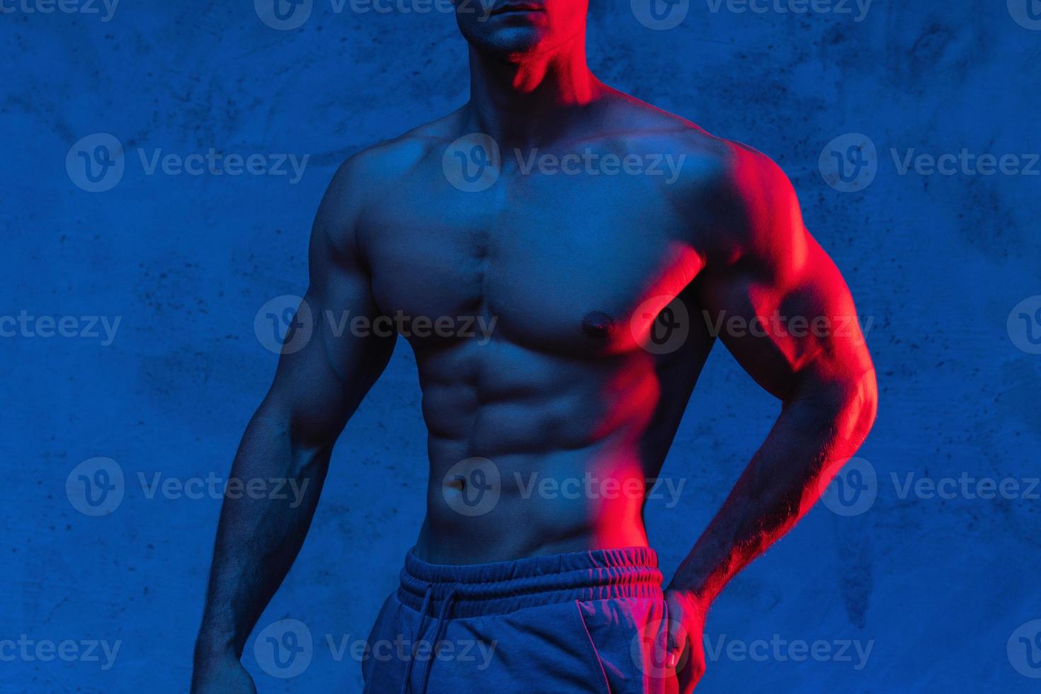 Bodybuilder is posing in the colorful neon light photo