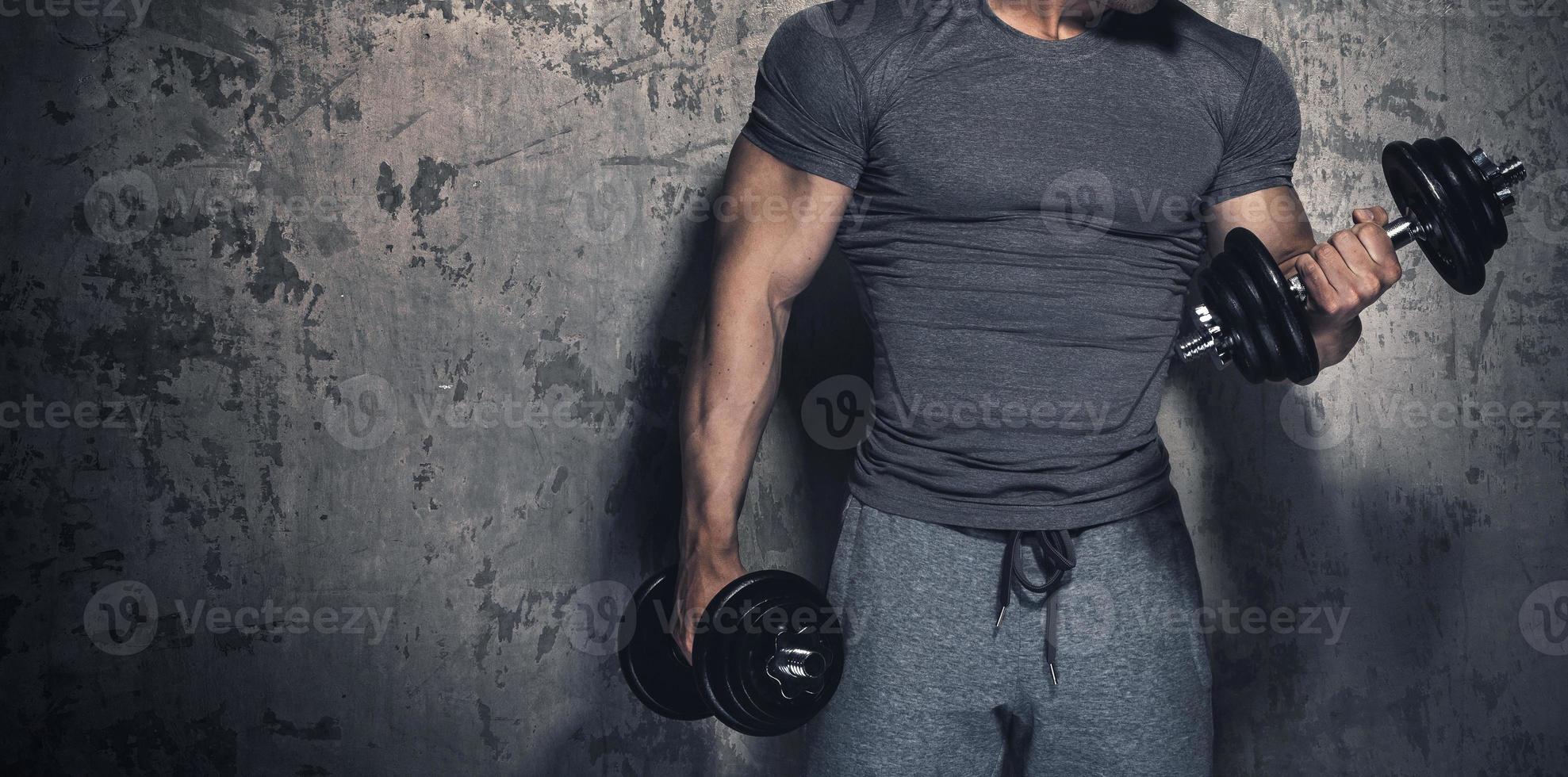 Bodybuilder is doing biceps curls with dumbbells photo
