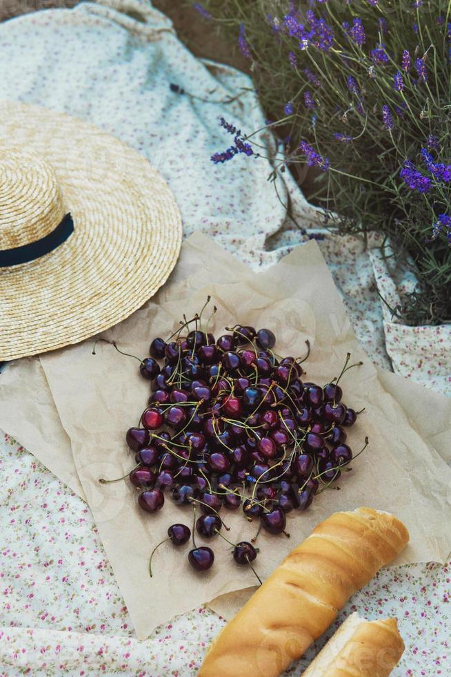 bayas de cereza y baguette en la manta durante el picnic en el campo de lavanda foto