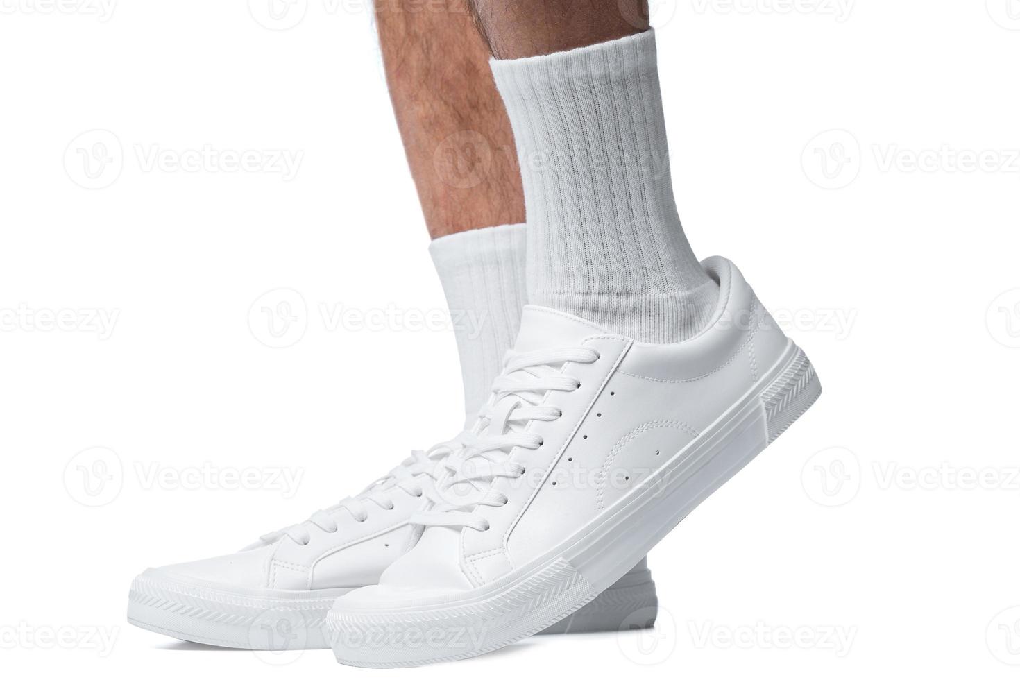 Closeup of male feet and shoes. Man wearing white trainers on white background. photo