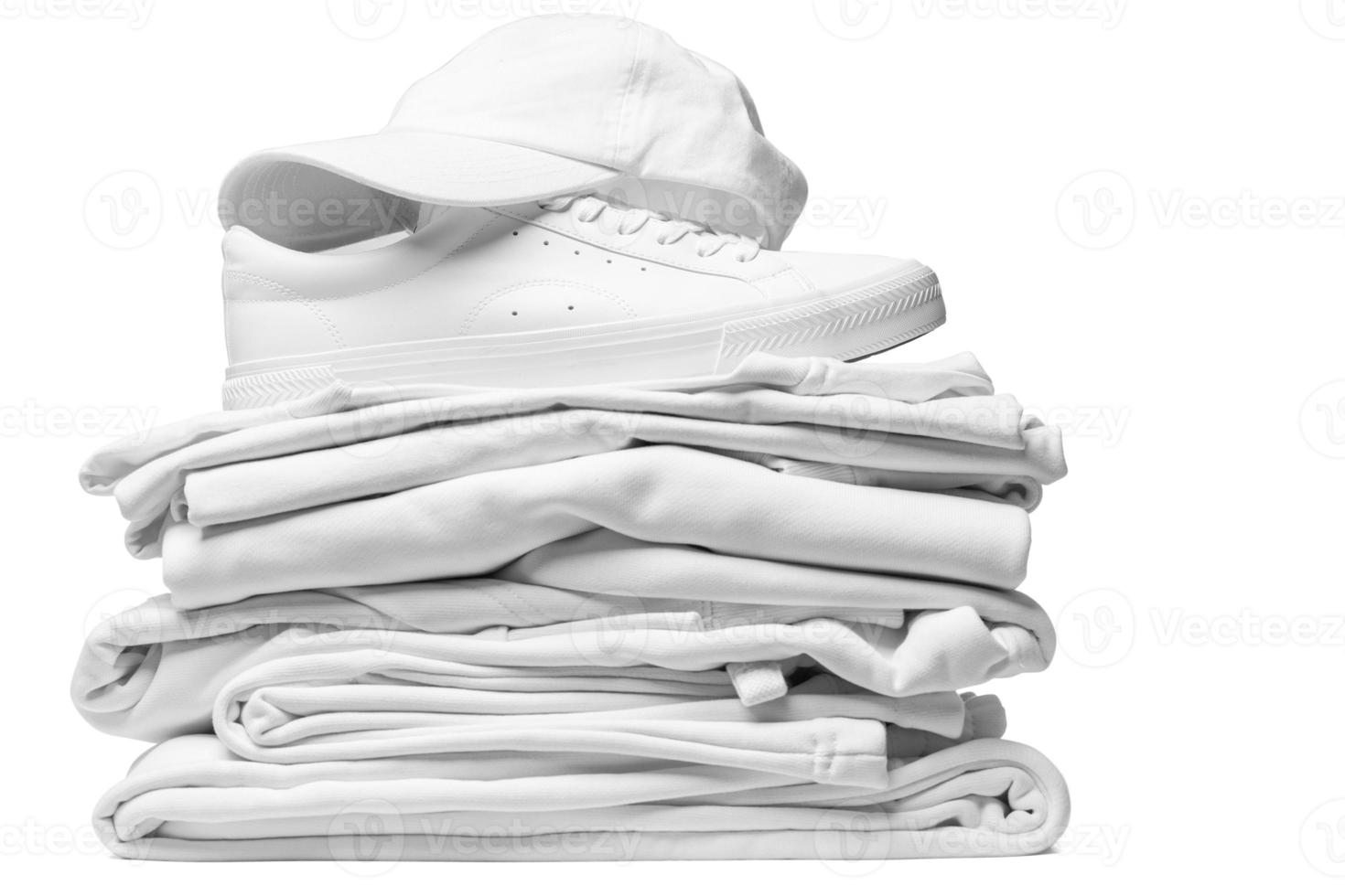 Stack of white clothes, trainers and baseball cap on white background photo