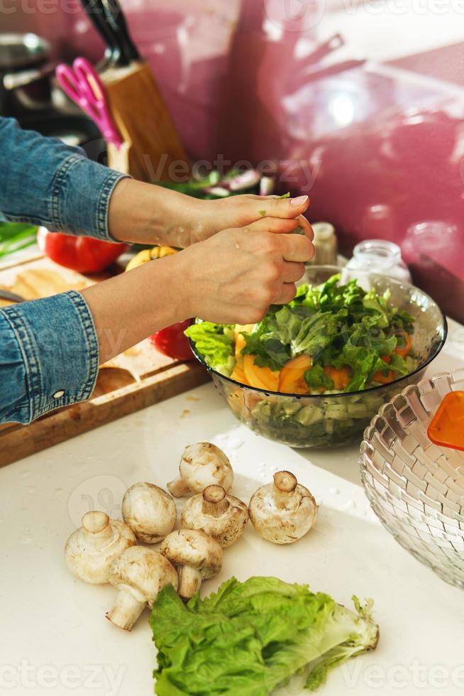 Woman is cooking vegetarian salad with fresh vegetables photo