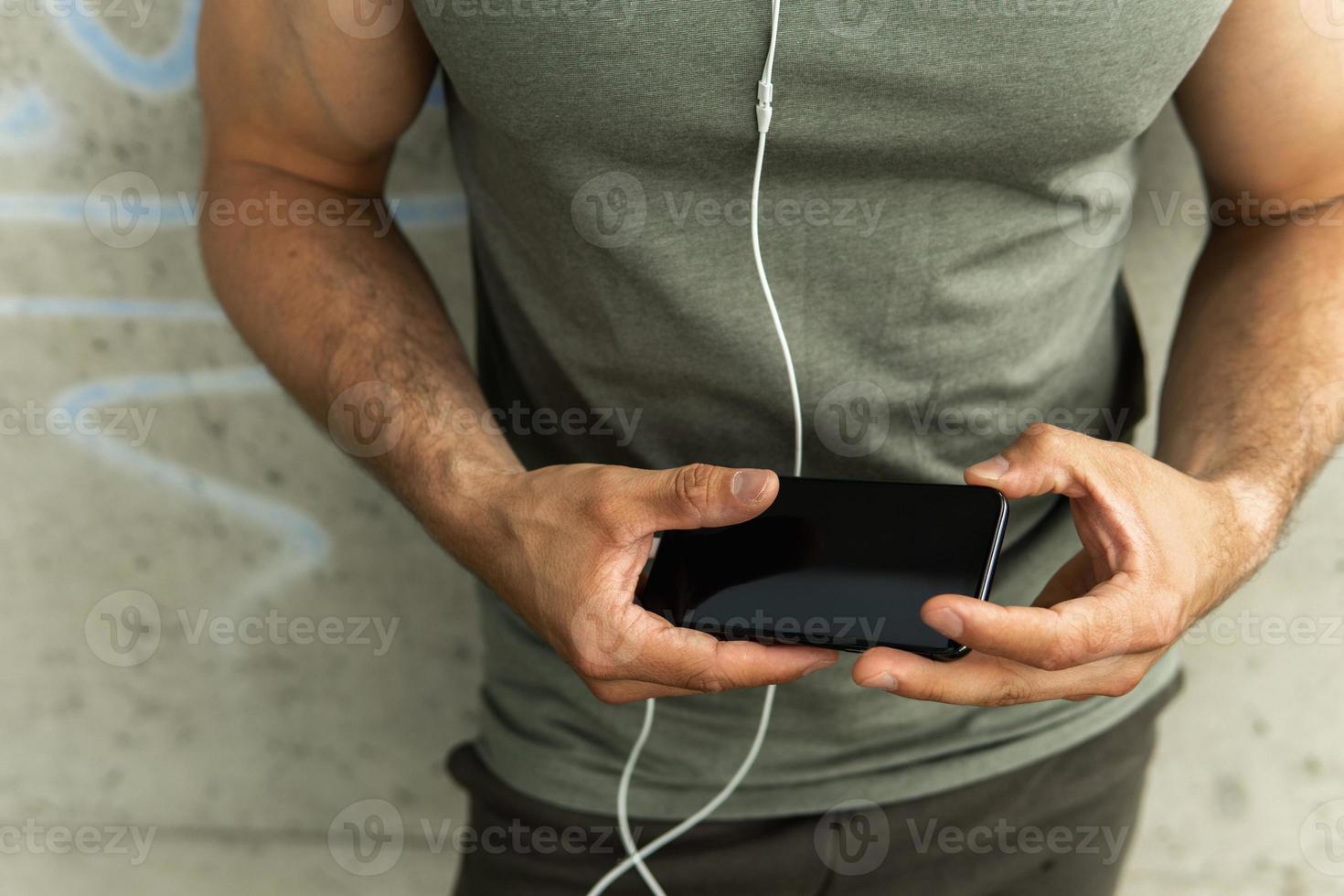 Athletic man holding black smartphone photo