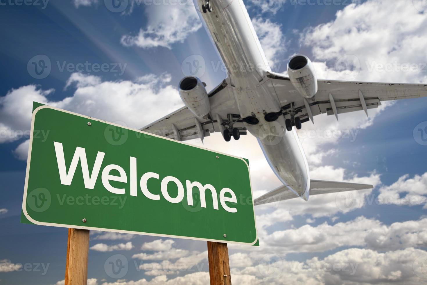 bienvenido señal de carretera verde y avión arriba foto