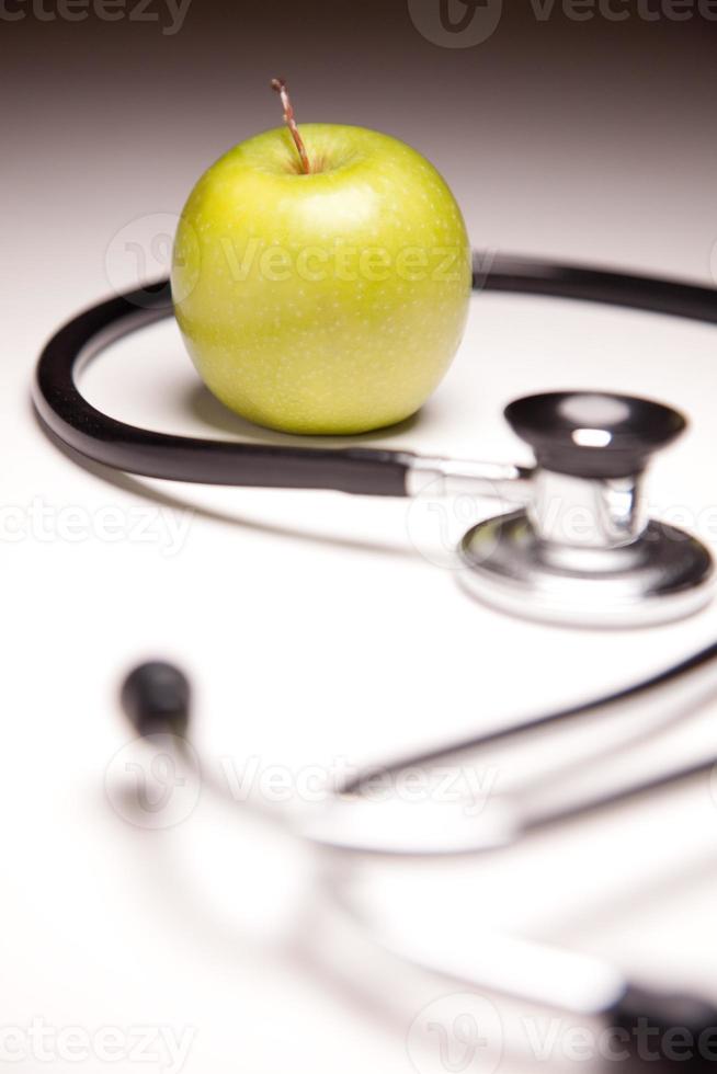 Stethoscope and Green Apple on Gradated Background photo