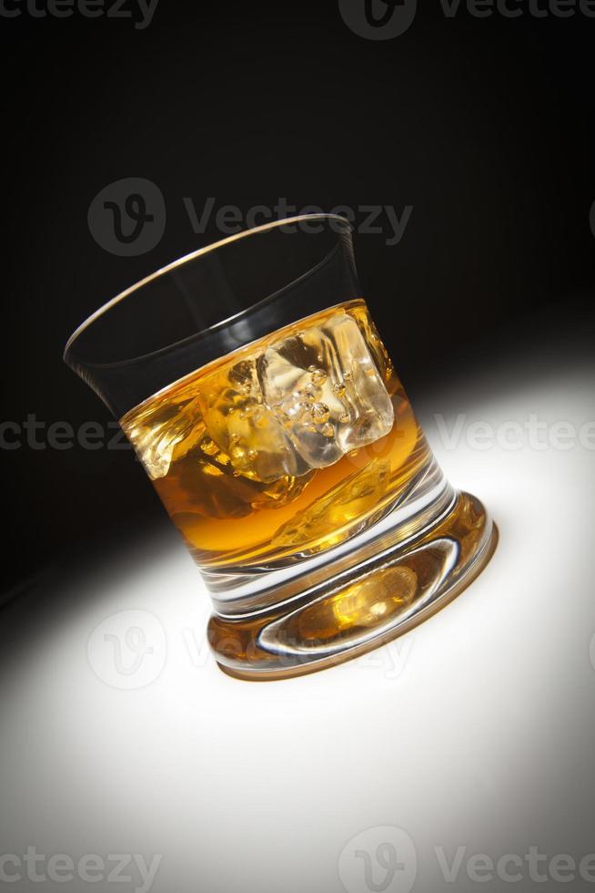 vaso de whisky y hielo bajo la luz del punto. foto