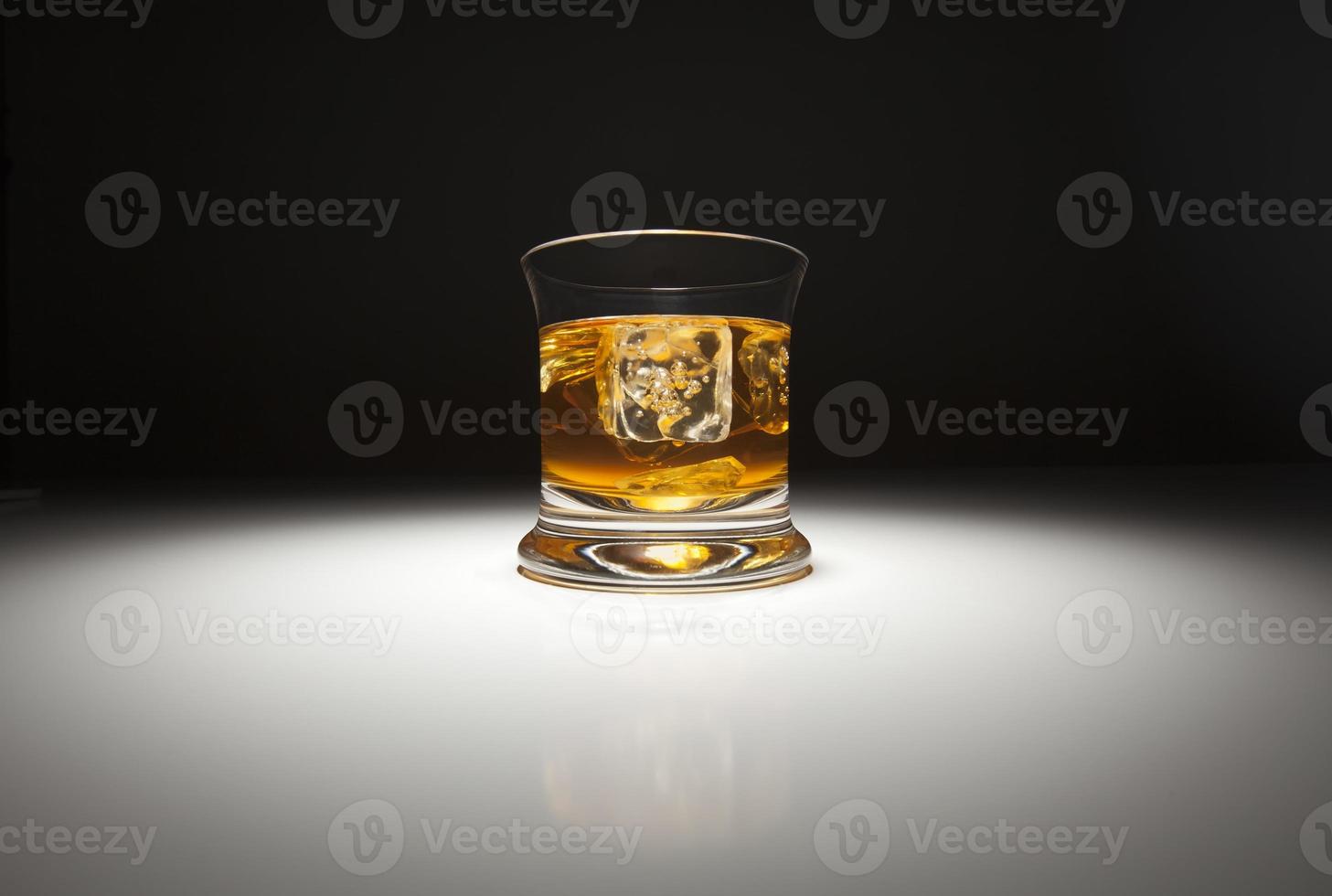 Glass of Whiskey and Ice Under Spot Light. photo