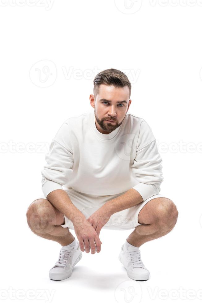 hombre guapo con sudadera blanca y pantalones cortos de fondo blanco foto