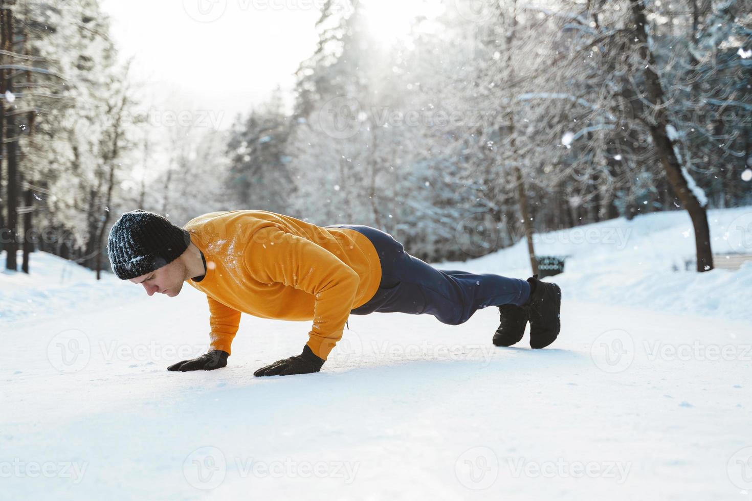 Athletic man doing push ups during his calisthenics winter workout photo