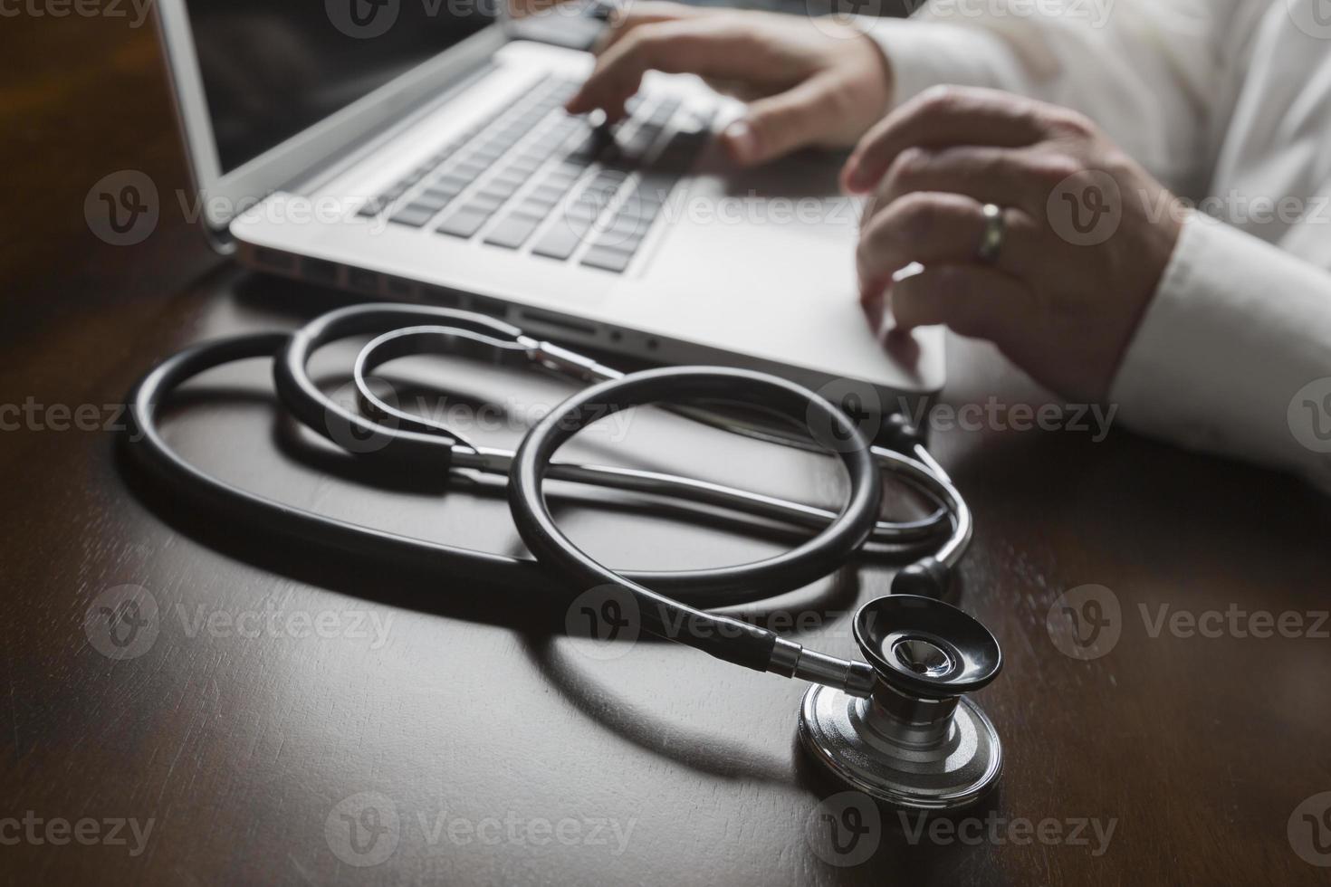 estetoscopio cerca del hombre escribiendo en la computadora portátil foto