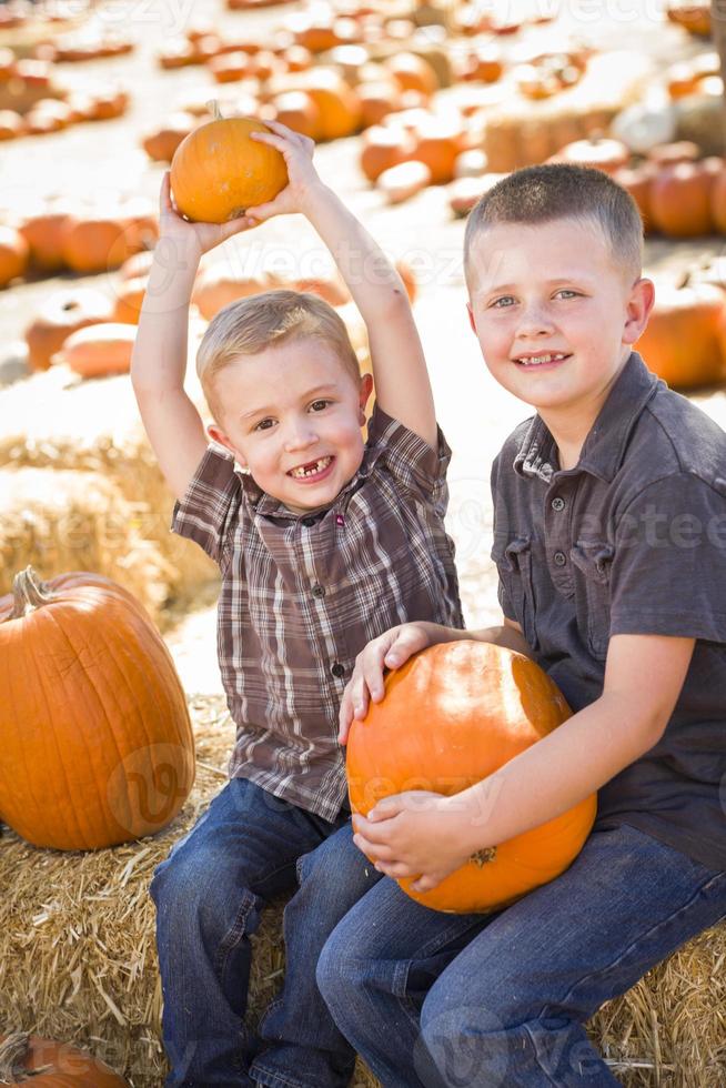 Two Boys Having Fun at the Pumpkin Patch on a Fall Day. photo