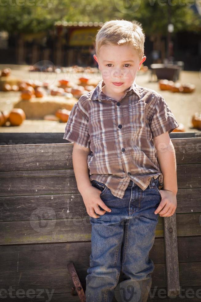Adorable Little Boy Standing Against Old Wood Wagon at Pumpkin Patch in Rural Setting. photo