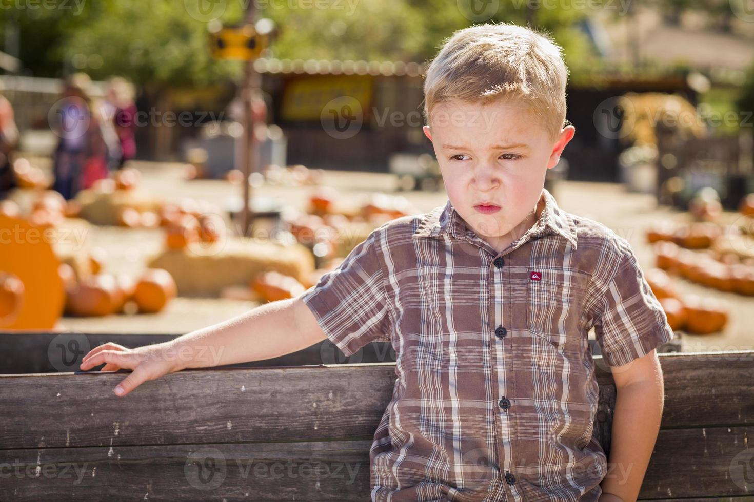 adorable niño parado contra un viejo vagón de madera en un huerto de calabazas en un entorno rural. foto