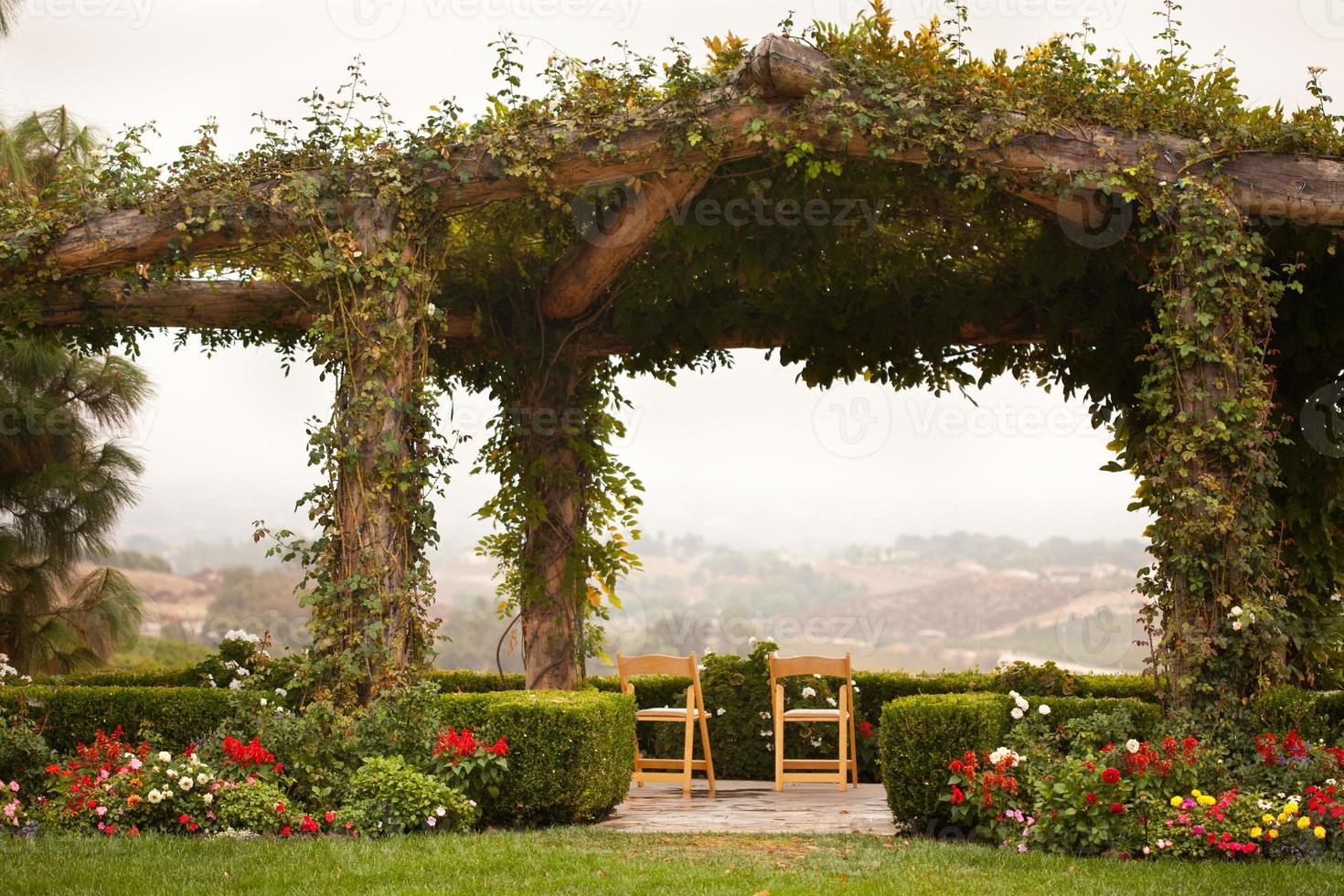 patio cubierto de enredaderas y sillas con vista al campo foto