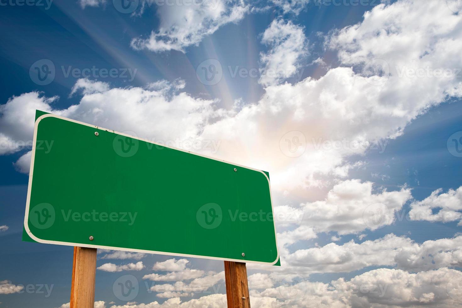 Blank Green Road Sign Over Clouds and Sunburst photo