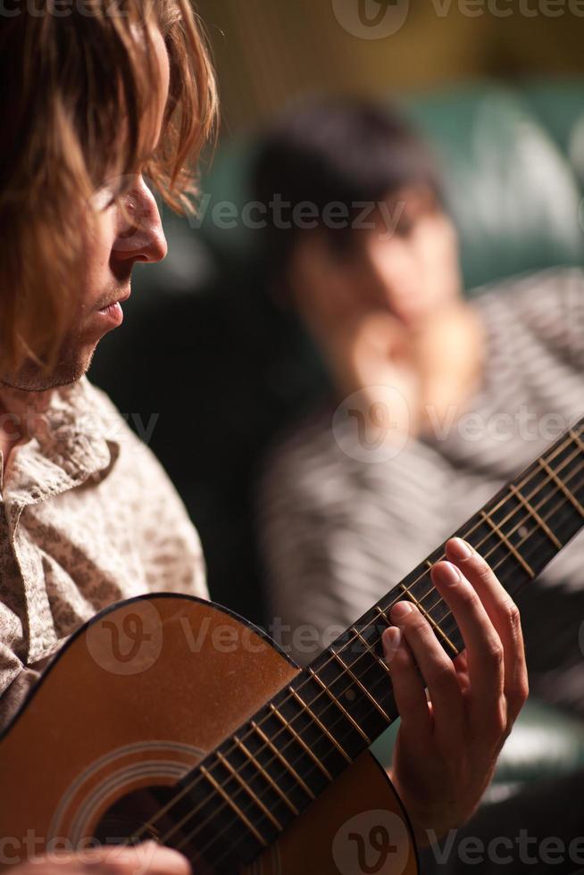 joven músico toca su guitarra acústica mientras un amigo escucha foto