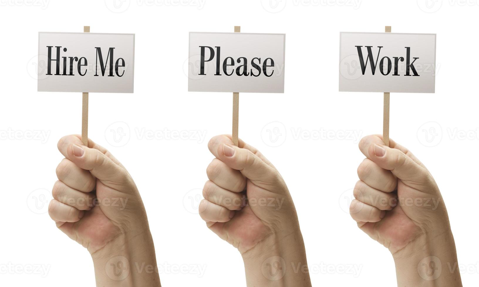 Three Signs In Fists Saying Hire Me, Please and Work photo