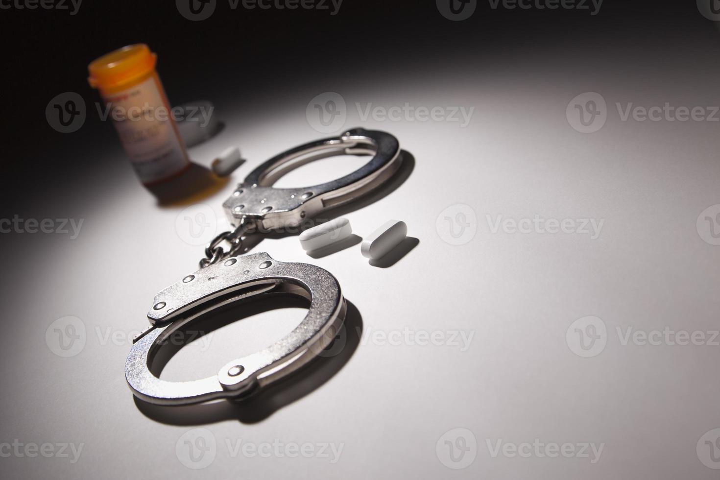 Handcuffs, Medicine Bottle and Pills Under Spot Light photo