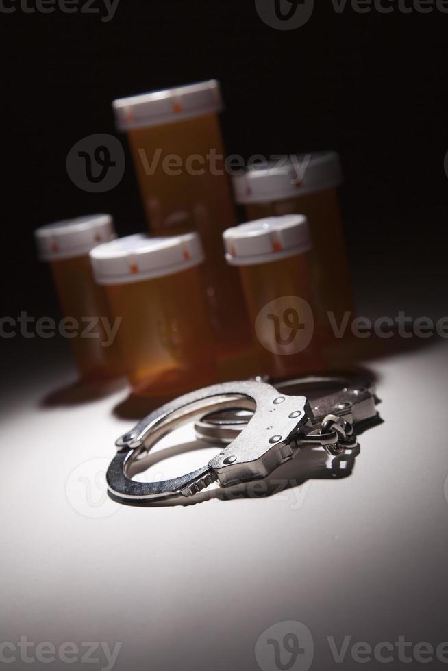 Handcuffs, Medicine Bottle and Pills Under Spot Light photo