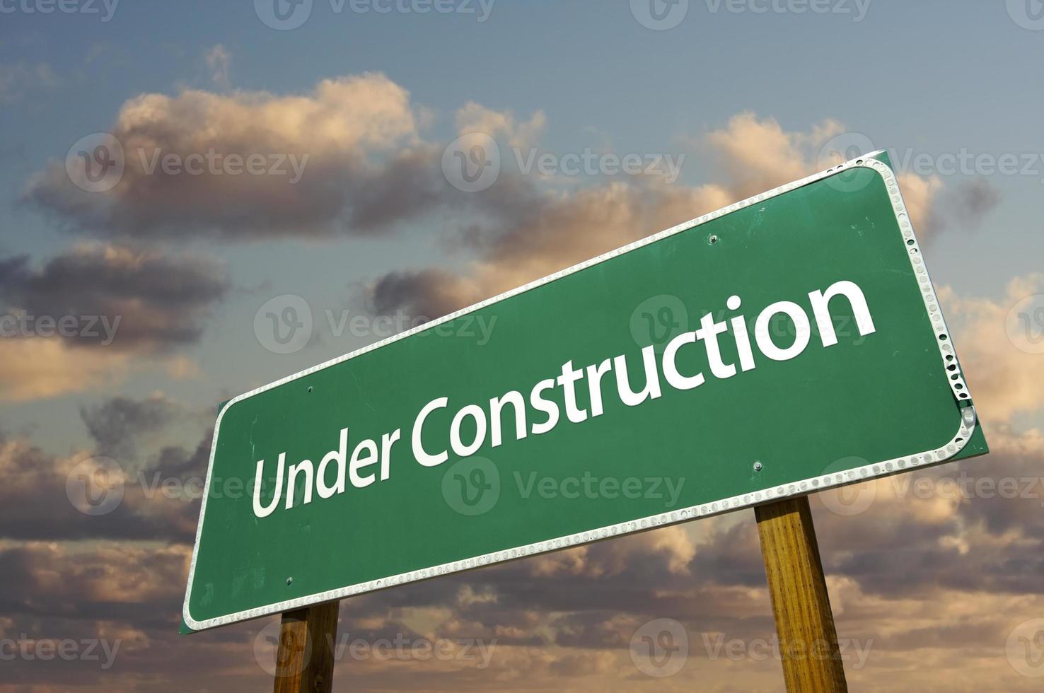 Under Construction Green Road Sign Over Clouds photo