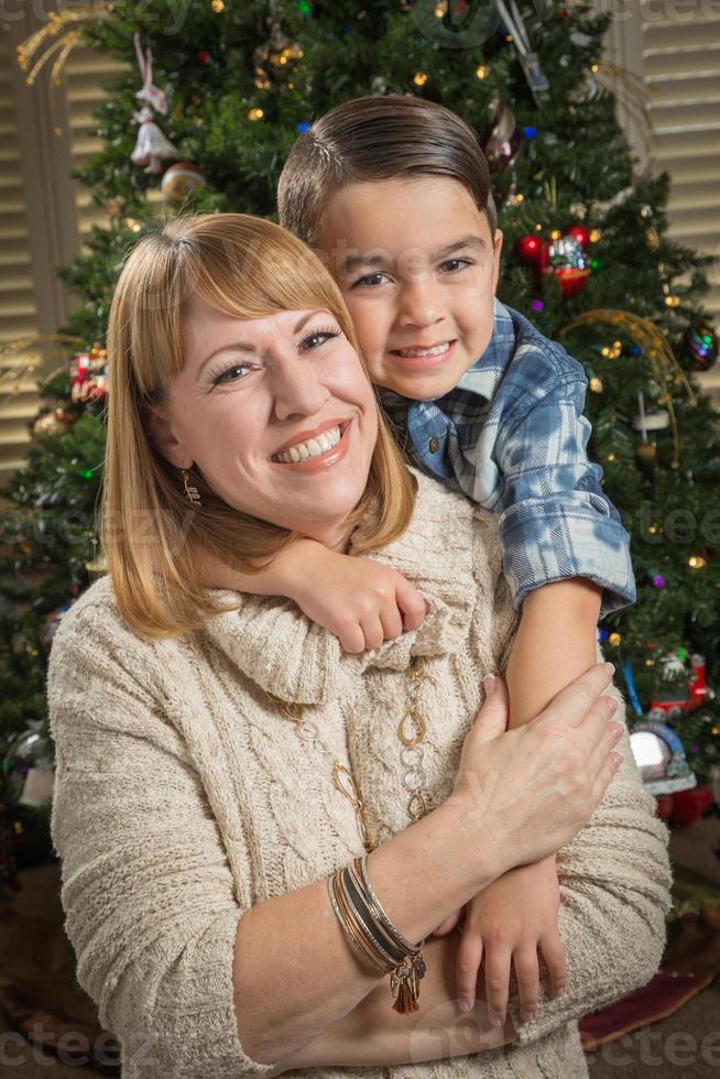 Mother and Mixed Race Son Hug Near Christmas Tree photo