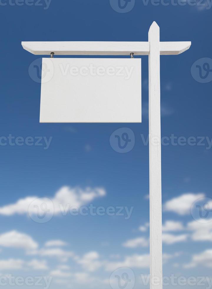 Blank Real Estate Sign Over A Blue Sky with Clouds. photo