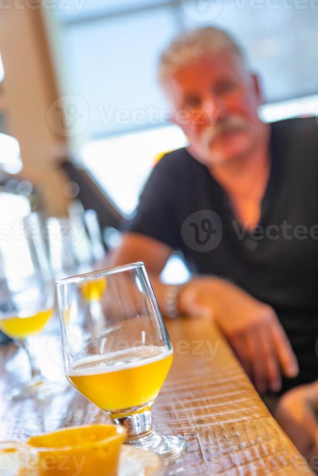 Glass of Micro Brew Beer On Bar With Handsome Man In Background. photo