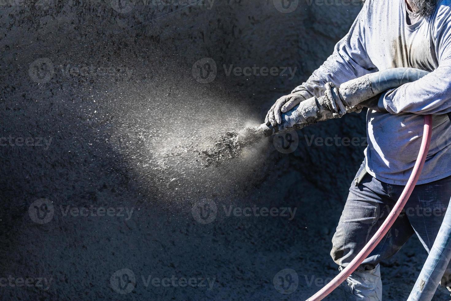 Pool Construction Worker Shooting Concrete, Shotcrete or Gunite Through Hose photo