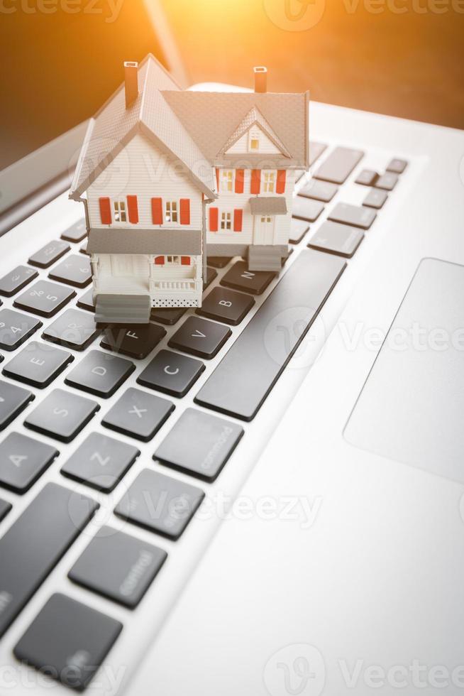 Miniature House And Laptop Computer Resting on Desktop. photo