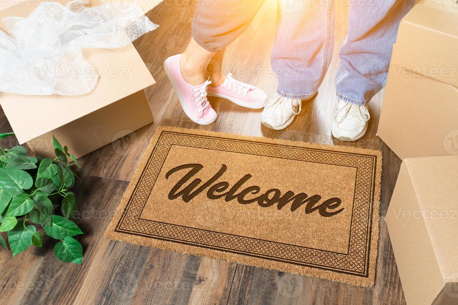 Man and Woman Standing Near Welcome Mat, Moving Boxes and Plant photo