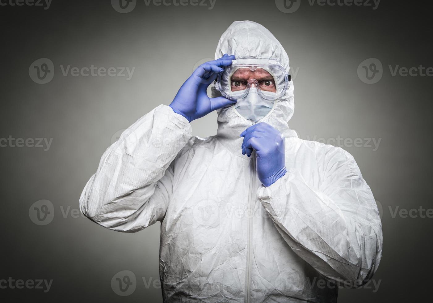 hombre con expresión intensa usando ropa protectora contra materiales peligrosos contra un fondo gris. foto