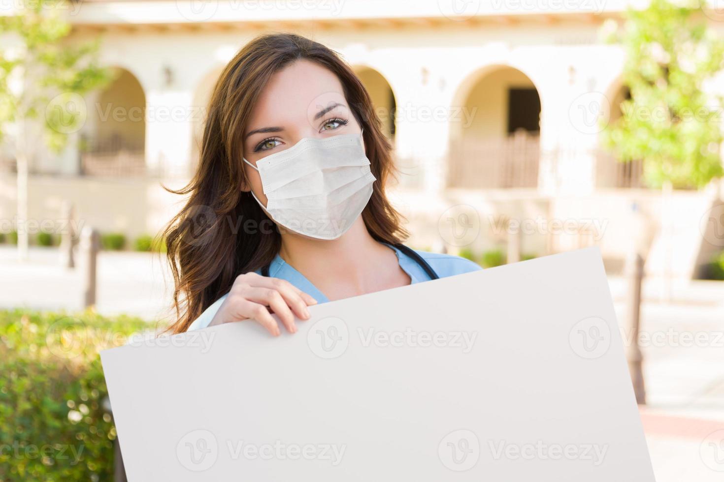 Female Doctor or Nurse Wearing Protective Face Mask Holding Blank Sign photo
