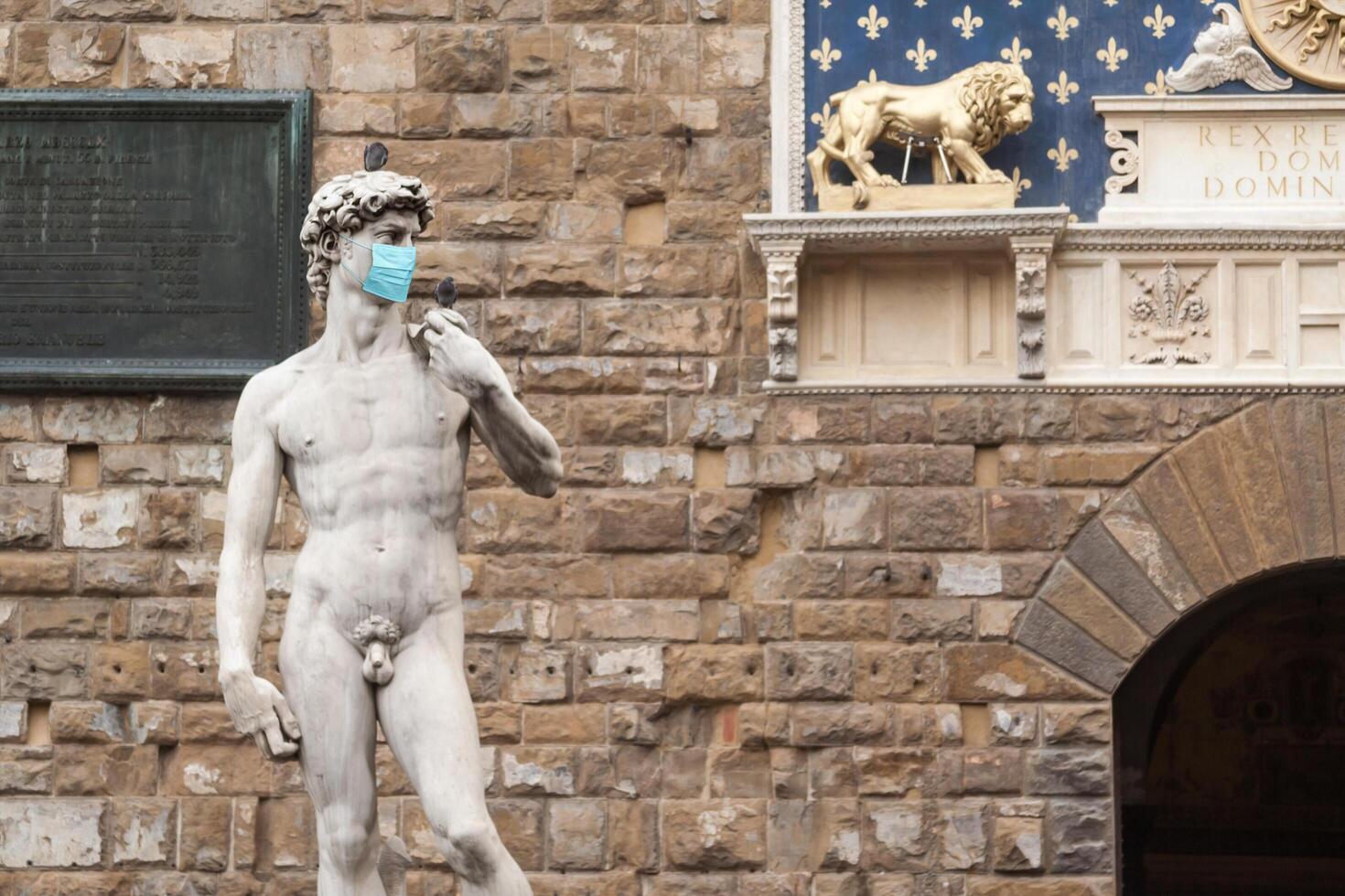 The Statue Of David in the Piazza della Signoria In Italy Wearing Blue Protective Medical Face Mask photo