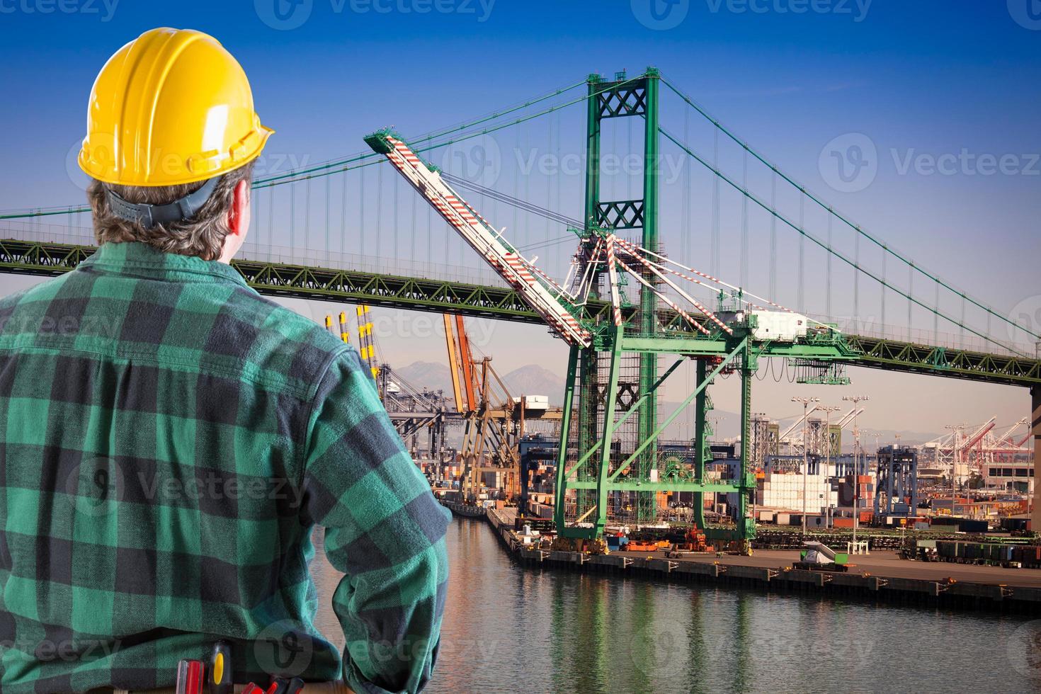 Male Worker Wearing Yellow Hard Hat Overlooking the San Pedro Ship Yard and Bridge. photo
