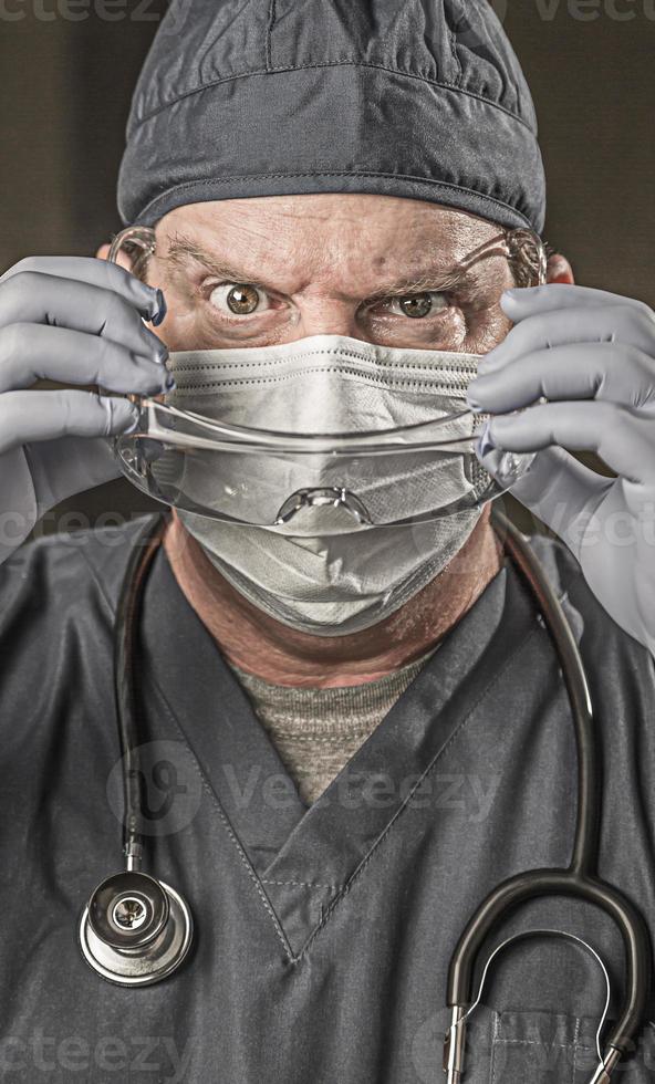Male Doctor or Nurse Wearing Scrubs, Protective Face Mask and Goggles photo