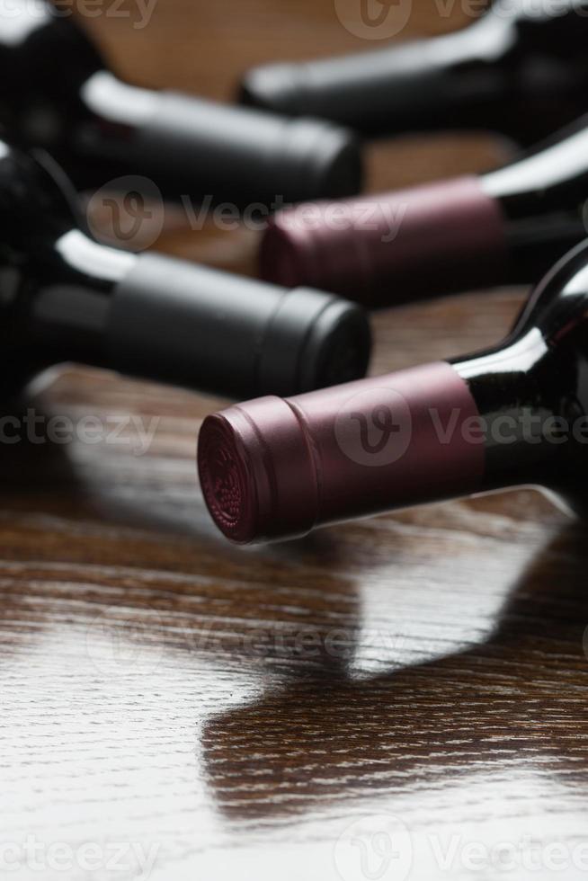 Various Wine Bottles on a Reflective Wood Surface Abstract. photo