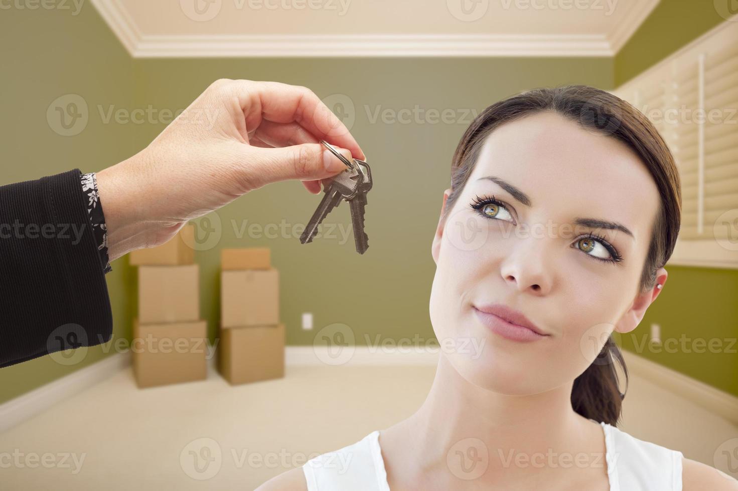 Young Woman Being Handed Keys in Empty Room with Boxes photo